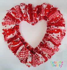 a red and white heart shaped wreath made out of pieces of fabric on a white background