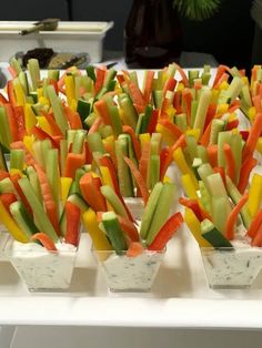 several trays filled with cut up vegetables on top of a white tablecloth covered table