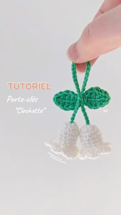 a hand is holding a crocheted bell ornament