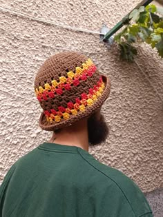 a man wearing a crocheted hat with flowers on it