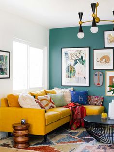 a living room with yellow couches and pictures on the wall above it, along with other decor items