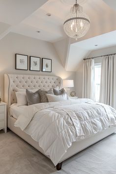 a large bed sitting under a chandelier in a bedroom next to a window