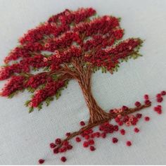 a close up of a cross stitch pattern on a white cloth with a red tree