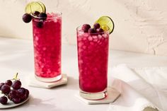 two glasses filled with fruit and garnish on a table