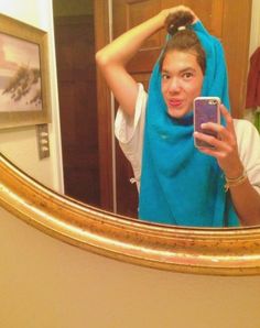 a woman taking a selfie in front of a mirror with a towel on her head