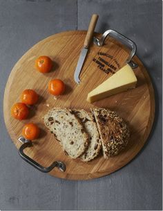 a cutting board with bread, oranges and cheese on it next to a knife