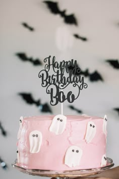 a pink cake with ghost decorations on it and a happy birthday sign in the middle