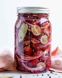 a jar filled with red onions on top of a white table next to a pink towel