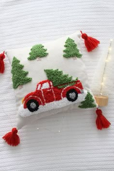 a red truck carrying a christmas tree on it's back is hooked up to a pillow