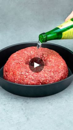 a hamburger bun being poured into a skillet with a bottle of beer in the background