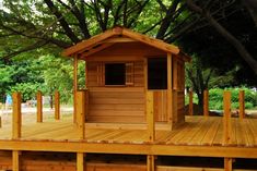 a small wooden structure sitting on top of a wooden platform next to trees and grass