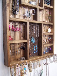 a wooden display case filled with lots of necklaces and earring hooks hanging from it's sides