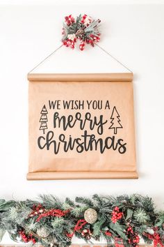 a christmas sign hanging on the wall above a mantel with stockings and garlands