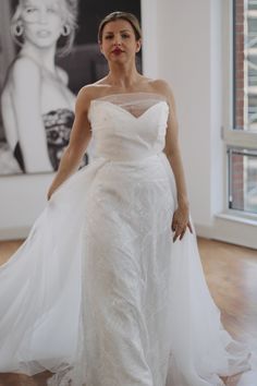 a woman in a white wedding dress is walking down the runway at an art gallery