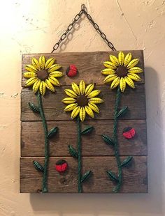 a wooden sign with sunflowers and daisies painted on the side, hanging from a chain