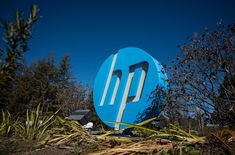 a large blue sign sitting on top of a lush green field next to trees and bushes