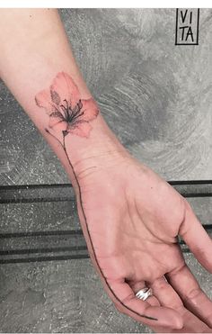 a person's hand with a flower tattoo on the left wrist and an arrow in the middle