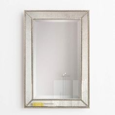 a large mirror hanging on the wall above a sink in a room with white walls