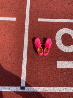 a pair of pink shoes sitting on top of a red tennis court with white lines