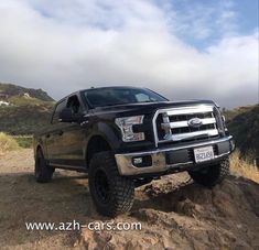 a black truck parked on top of a dirt hill