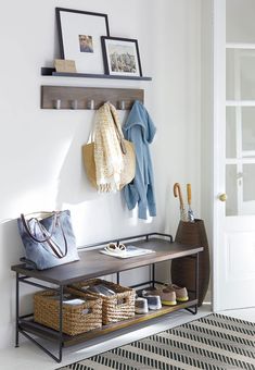 a coat rack with baskets and purses on it in front of a white wall