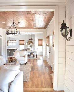 an instagram photo of a living room with white couches and wood ceilinging