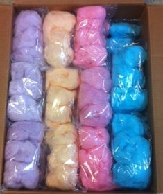 a box filled with different colored doughnuts in plastic wrappers on top of a table