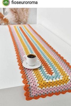 a crocheted table runner with a cup of coffee on it and an image of a cat in the background