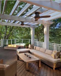 an outdoor living area with couches, tables and fire pit on the decking