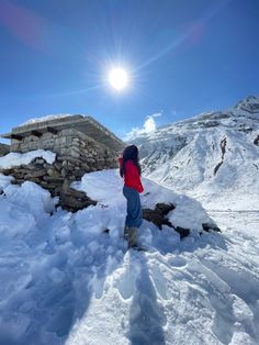 a person standing in the snow looking at something on top of a hill that is covered with snow