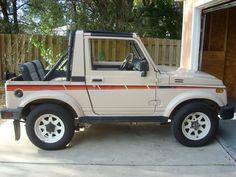 an off - road vehicle parked in front of a garage with its door open and the driver's seat up