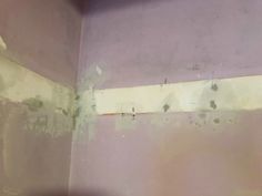 the corner of a room that has been painted purple and white with peeling paint on it