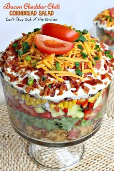 a layered salad in a glass dish with bacon, corn and tomatoes on top is ready to be eaten