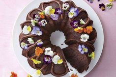 a chocolate bundt cake with flowers on it sitting on top of a white plate