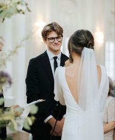 a man and woman standing next to each other in front of a wedding ceremony arch