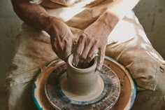 a man is making a vase on a potter's wheel, with his hands