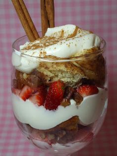 a dessert in a glass with cinnamon sticks sticking out of the top and whipped cream on top