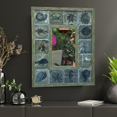 a mirror that is on the side of a wall next to a vase with flowers