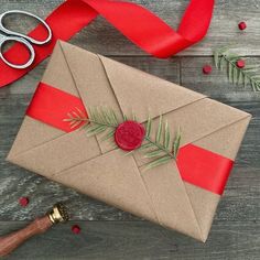 an envelope wrapped in brown paper with a red ribbon and a wax stamp on it