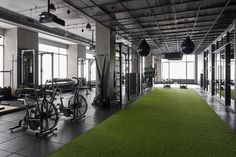 an indoor gym with green carpeting and exercise equipment on the walls, along with large windows