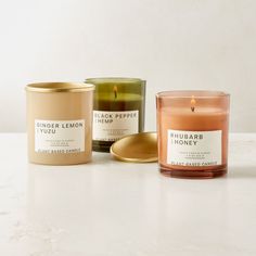 three candles sitting next to each other on a white counter top with one candle in the middle