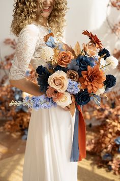 a woman in a white dress holding a bouquet of blue, orange and pink flowers