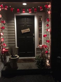 the front door is decorated for christmas with red lights and paper lanterns hanging from it