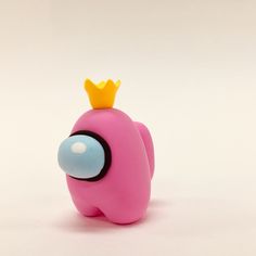 a pink toy with a yellow crown on it's head sitting in front of a white background