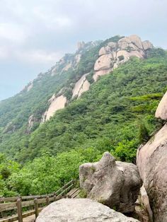 large rocks on the side of a mountain with green trees in the backgroud