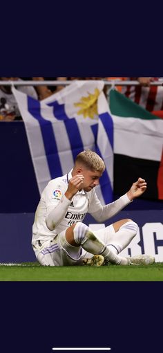 a soccer player sitting on the ground with his head in his hands