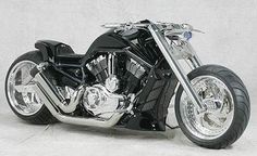 a black and chrome motorcycle parked in front of a white wall with no one on it