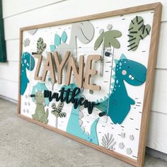 a wooden sign that says,'zaynne mitter'with dinosaurs and leaves on it