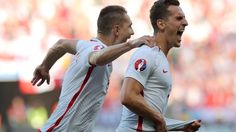 two soccer players are celebrating their goal in front of an audience at a stadium or arena