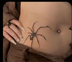 a woman's stomach with a spider tattoo on it